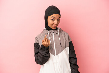 Young Arab woman with sport burqa isolated on pink background pointing with finger at you as if inviting come closer.