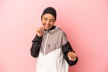 Young Arab woman with sport burqa isolated on pink background dancing and having fun.