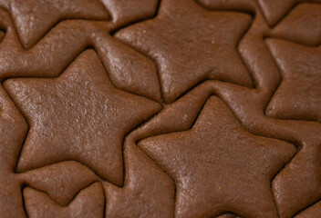 Closeup of Woman's hand cutting homemade gingerbread cookies on wooden background. Christmas baking concept.