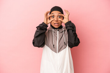 Young Arab woman with sport burqa isolated on pink background keeping eyes opened to find a success opportunity.