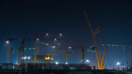 Construction site at night. Construction of the bengal nuclear power plant. Tower cranes at a...