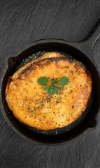 Top view of grilled provolone cheese served in a black pan.