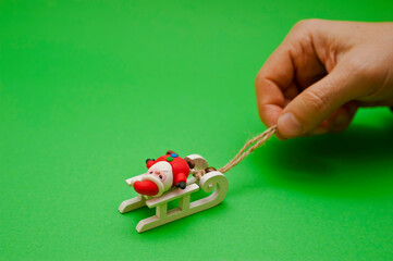 male hand pulling a Santa Claus figurine on a sledge - Powered by Adobe