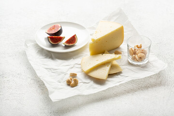 Cheese pieces on wrapping paper and fig fruits food on light surface