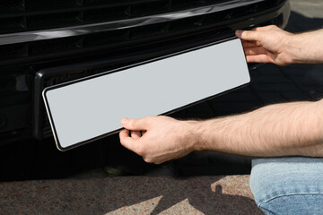 Man installing vehicle registration plate outdoors, closeup