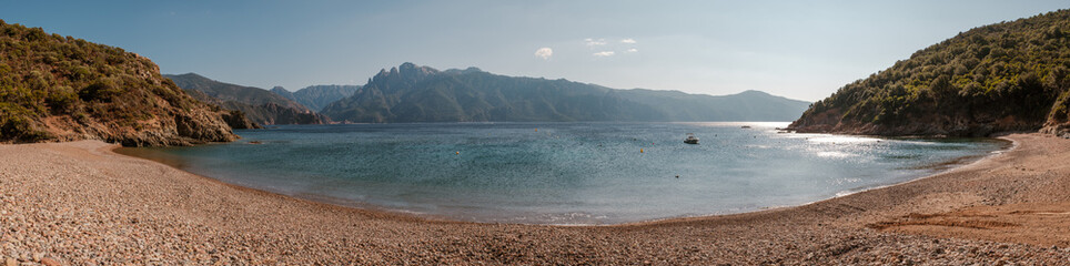 Panoramic view of Plage de Gradelle beach in Corsica with the tower of Porto and mountains in the distance