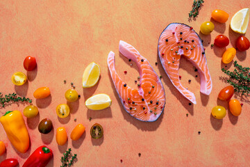 Creative aesthetic artistic food photography. Flat lay picture of organic fresh raw salmon, tomatoes, peppers, lemons, herbs and spices on the light peach background. Still life art photo.