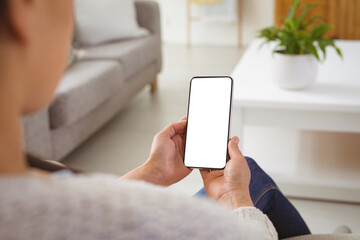Asian woman sitting on sofa, using smartphone with copy space on screen