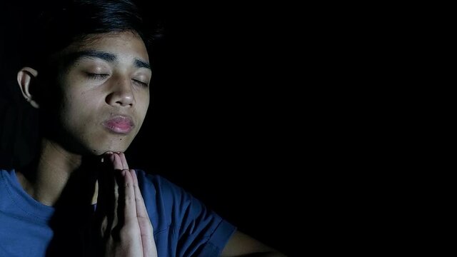 A Male Asian Praying In Darkness