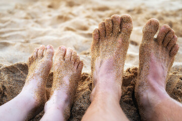 Füße von Vater und Sohn an einem Strand im Sommerurlaub