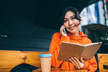 Positive ethnic woman freelancer talking on smartphone