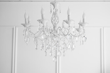 Vintage white chandelier decorated with beads or crystals over white wall