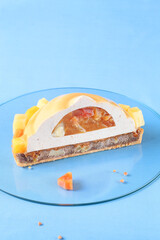Contemporary Tropical Fruit Multi-Layered Mousse Tart on blue background.
