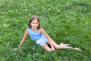 a cheerful girl of 8-10 years old plays on a green meadow on a warm summer day, walks in the fresh air, joy and happiness