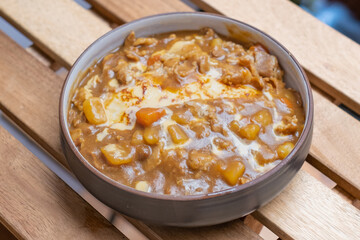 Delicious Japanese sliced meat curry serve with omlete rice and vegetables, curry Rice in black plate on a wooden table with copy space.
