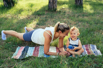 Fototapeta premium mother with her baby boy do physical exercises outdoor in park