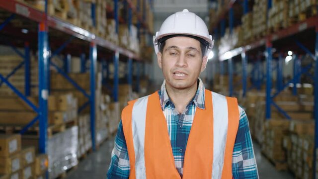 A Caucasian worker has an interview talking and looking at the camera in the distribution warehouse