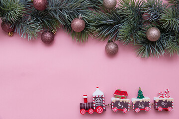 Christmas tree branch decorated with Christmas balls and a toy train. New Year card, top view, flat lay.