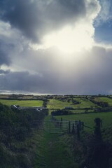 clouds, bright sun over green fields 