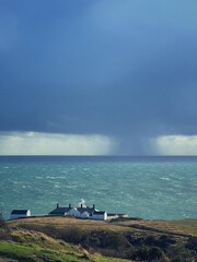 view of the sea with lighthouse and rain clouds