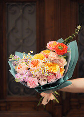  Colorful flowers assorted bouquet in bright paper. Holiday celebration concept. Bouquet of beautiful flowers in hands. Colorful flowers bouquet wrapped in paper