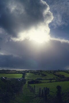 clouds, bright sun over green fields 