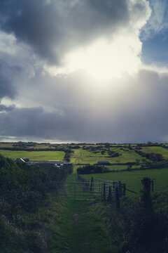 clouds, bright sun over green fields 
