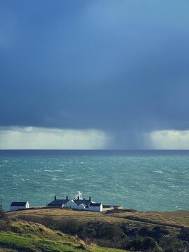 view of the sea with lighthouse and rain clouds