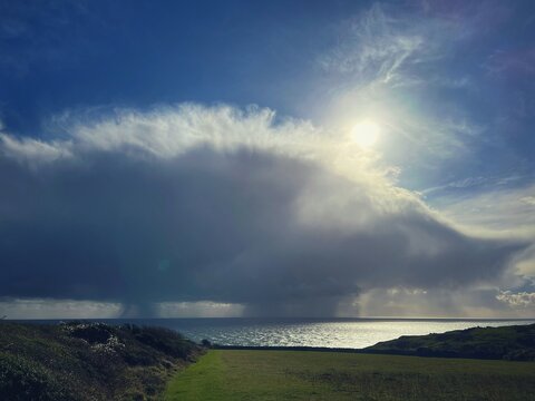 storm clouds over sea and green fields