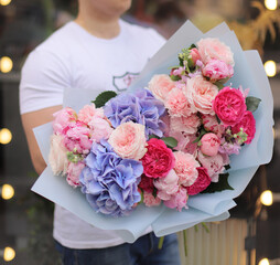 Strong man holding a delicate bouquet of beautiful flowers in his hands. Colorful flower bouquet. Wrapped flowers bouquet.