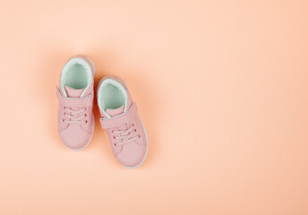 Cute pink children's sneakers. Orange background. Baby clothes and shoes. Flatlay,copy space