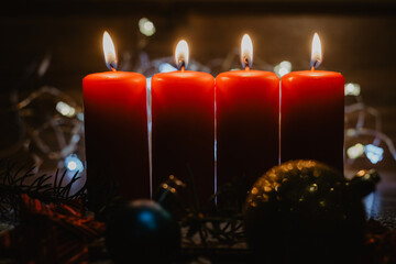 Four red advent candles with four candles lit and christmas decoration lying in snow as template