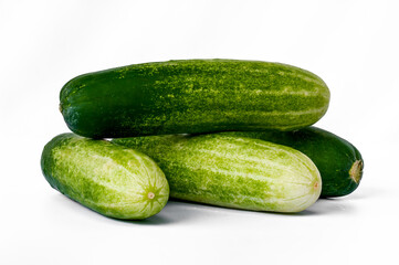 Four cucumbers for greens, in a stack composition, isolated on a white background, copy space