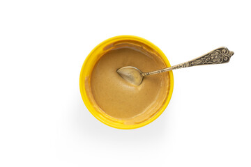 Mustard served in a bowl with a little spoon, isolated on white background