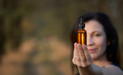 Female holding a dropper bottle of herbal essential oil. Flower therapy BACH, concept. Copy space...