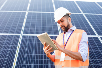 Engineer with a tablet stands on the background of a solar station