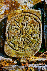 Elaborate mandala carved in an old stone on trail through Himalayan valleys. The world largest and highest mountain range, in Nepal. Oil Paint filter.