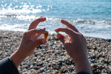 Marine colored glass of a round shape in hands on the background of the sea