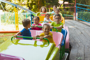 The happy kids on a roller coaster in the amusement park
