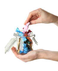 Woman taking candy in light pink wrapper from glass jar isolated on white, closeup