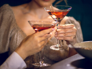 Two women holding glasses of Martini with a woman on background