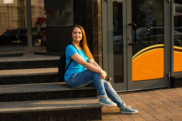 The happy student girl in casual clothes is posing in the city