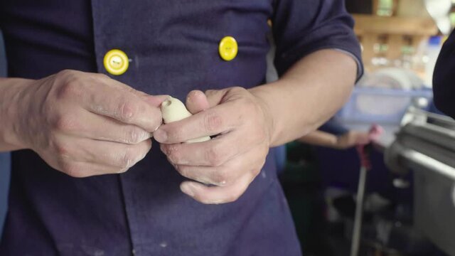 Man Hands Preparing Typical Venezuelan Pastry Teque&ntilde;os in a Kitchen in Marine Blue Uniform