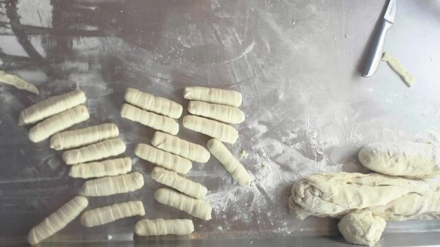 Close Up of Typical Venezuelan Pastry Teque&ntilde;os Rolling on a Stainless Counter in a Restaurant Kitchen