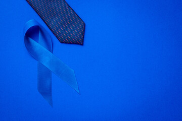 Cancer awareness blue. Blue ribbon, fashion tie isolated on deep blue background. Awareness...