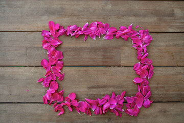 Ein Rahmen aus Rosen Blütenblättern auf Holz mit Negativraum