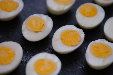 Many halves of boiled chicken eggs lying on table closeup background