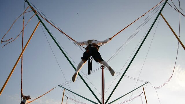 Little happy girl having fun in the park and jumping on the tramline against the blue sky