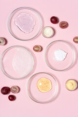 Obraz na płótnie Canvas Cosmetic products, scrub, face serum and gel in many petri dishes on a pink background. Natural cosmetics from herbal ingredients.