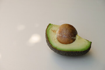 A piece of avocado. Pulp and seeds. Sunlight. Outdoor. Copy space.